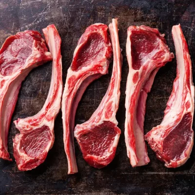 Côtelettes d’agneau crues sur planche en bois, proposées par la Boucherie Vigne & Fils à Montélimar